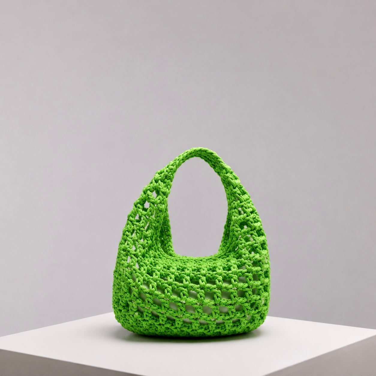 A bright lime green crocheted shoulder bag with an openwork pattern and a single top handle. Designed by ZOEL for summer strolls from day to night.