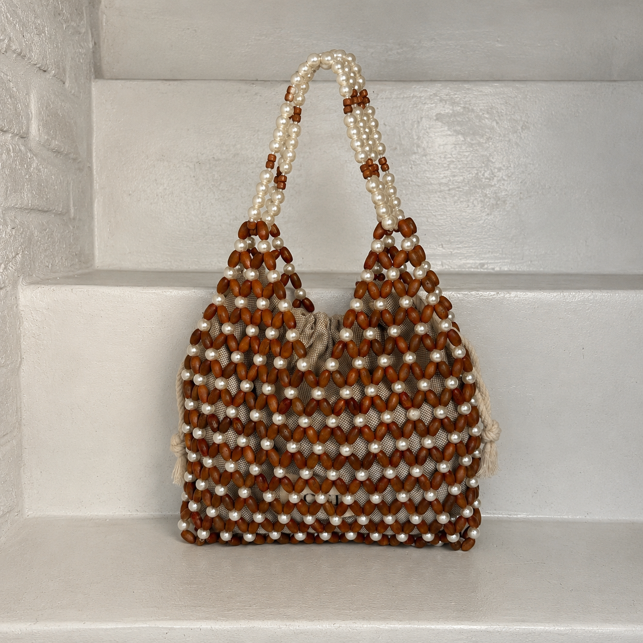 A handmade beaded shoulder bag made of brown wooden beads and white faux pearls by ZOEL