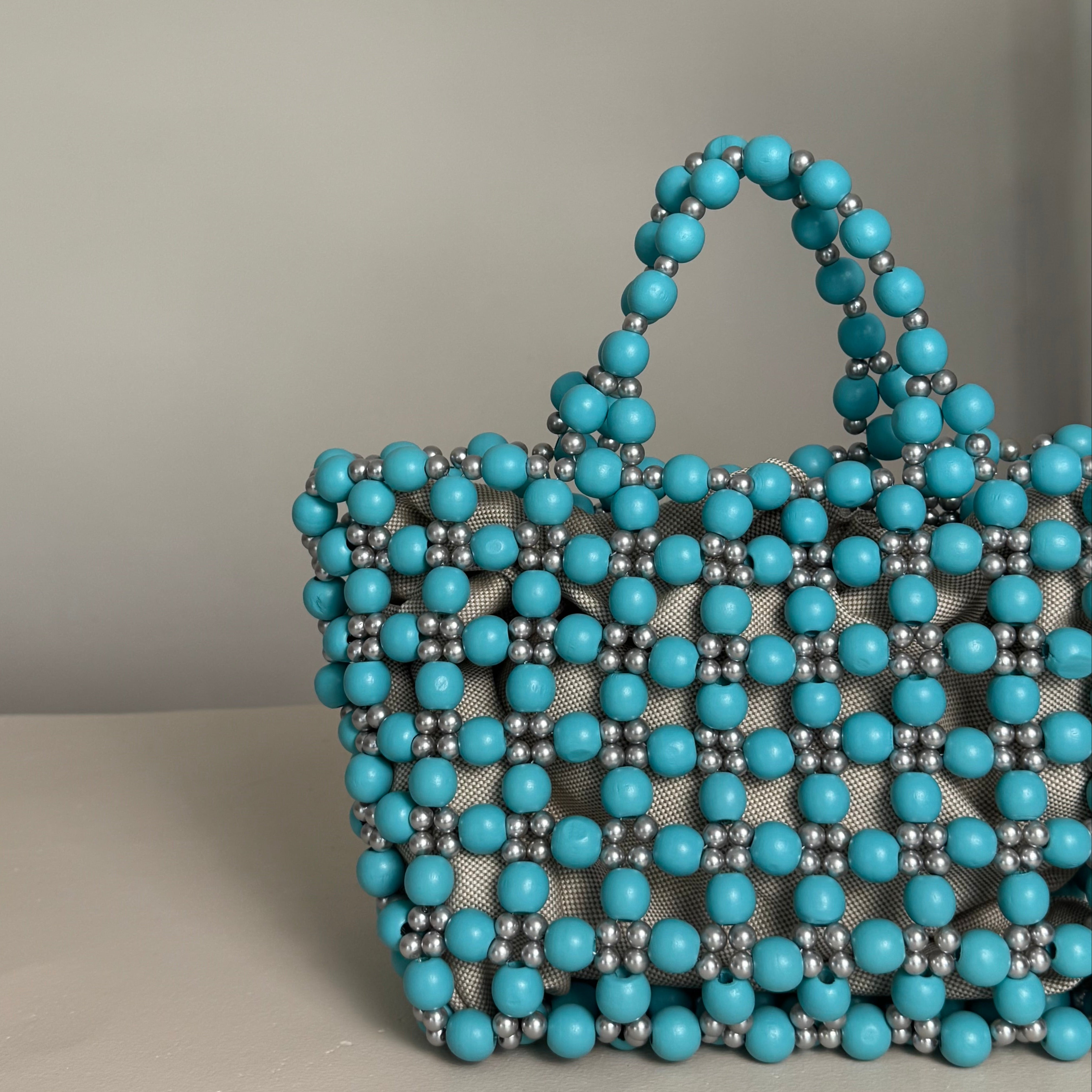 Turquoise and silver beaded handbag on a neutral background. wooden tote bag with silver pearls made my ZOEL
