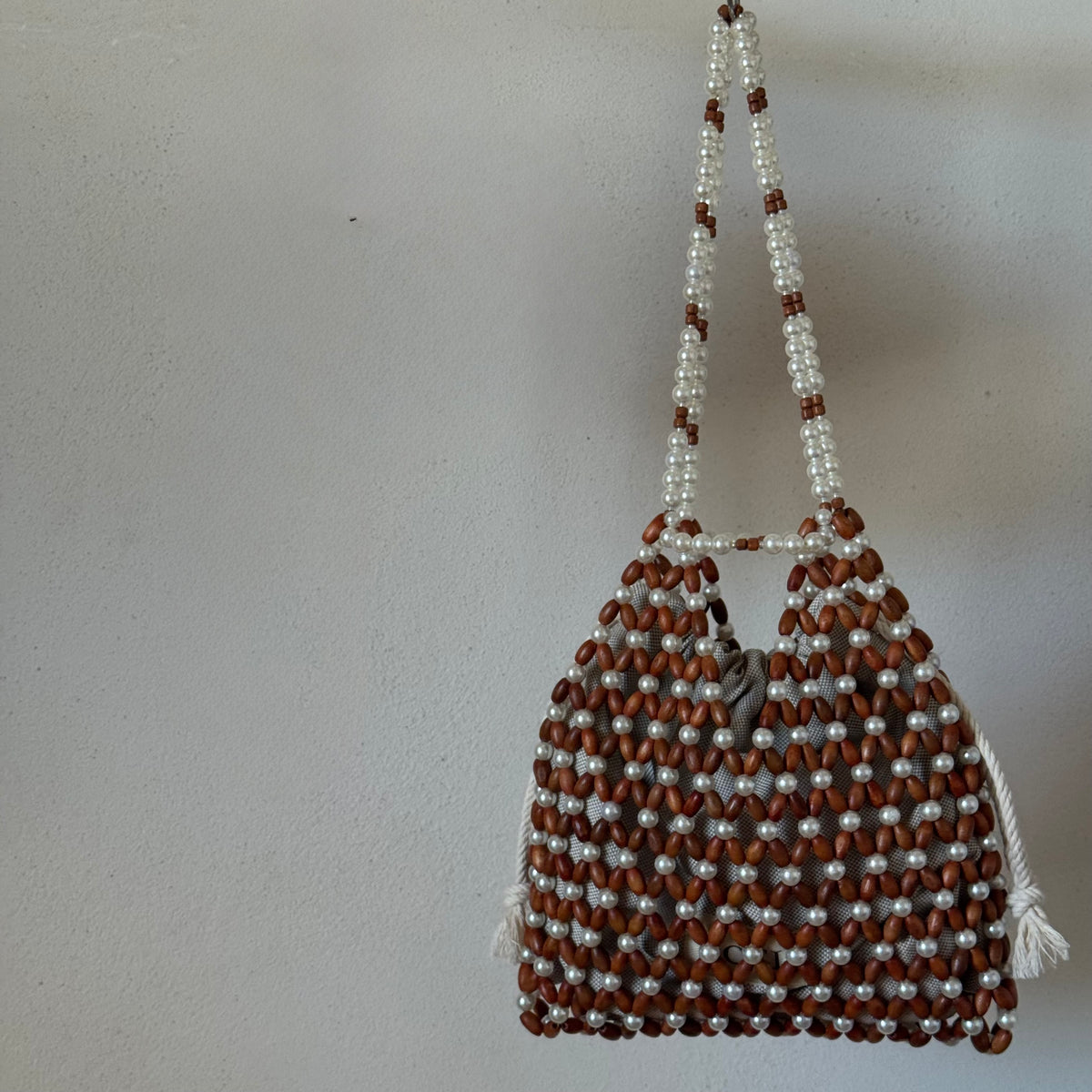 A handmade beaded shoulder bag made of brown wooden beads and white faux pearls, by ZOEL